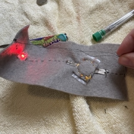 This is showing the conductivity tester working using conductive thread, conductive fabric, a battery, light, and sowing needle. I managed to shock myself so many times making this my hands were really tingling after.